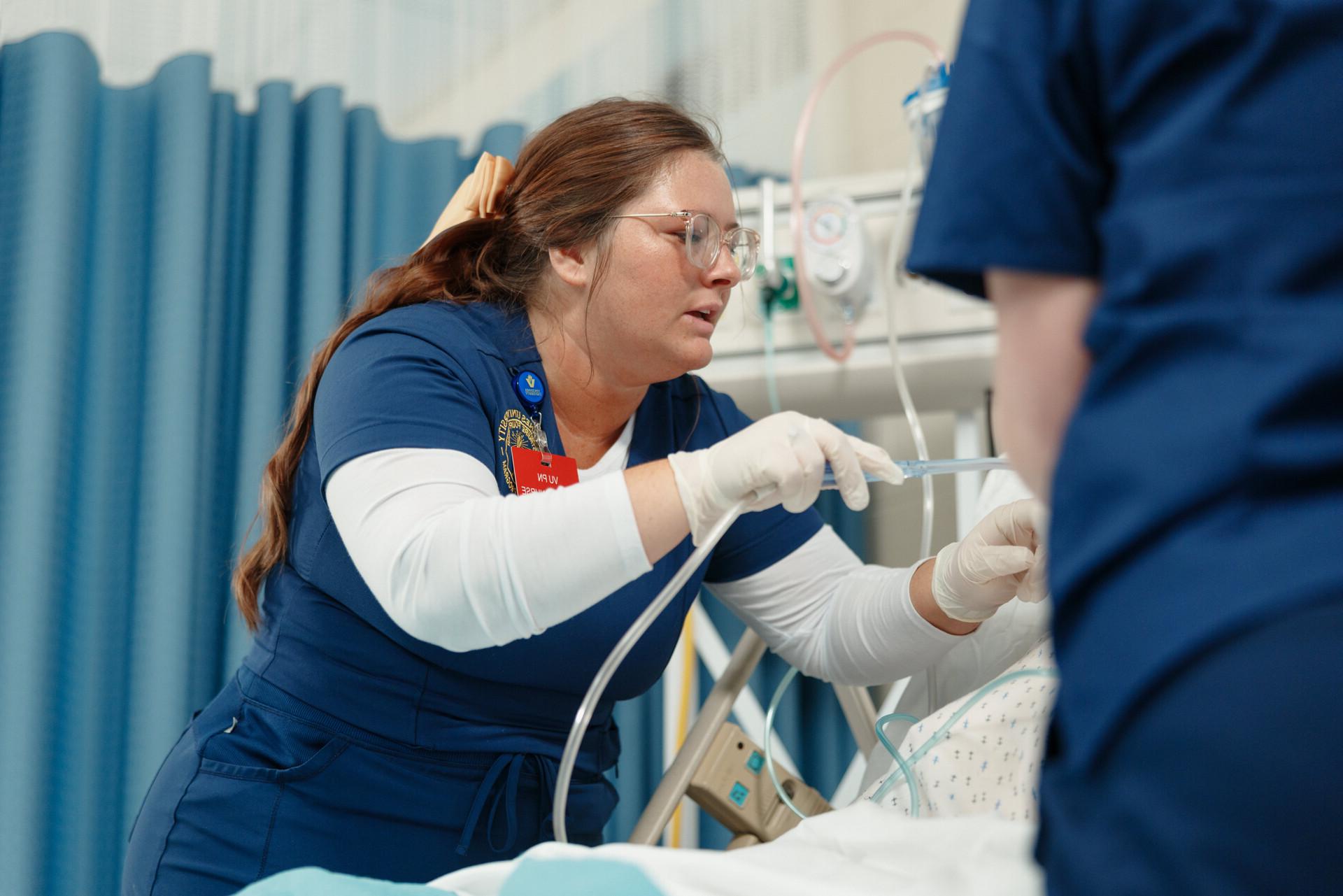 A group of nursing students practicing using needles on a training arm