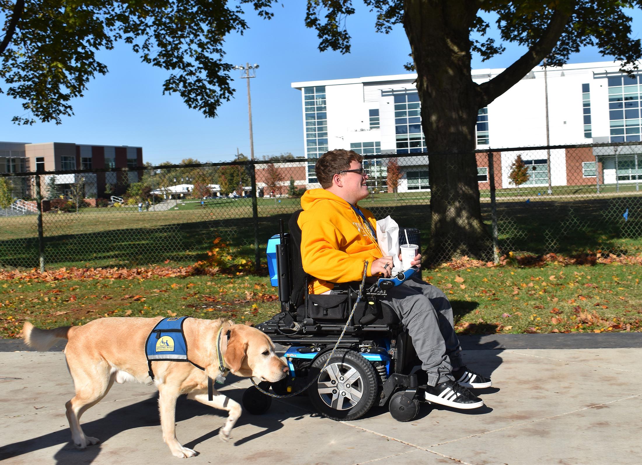 A student and their service dog going for a walk in front of the dining center