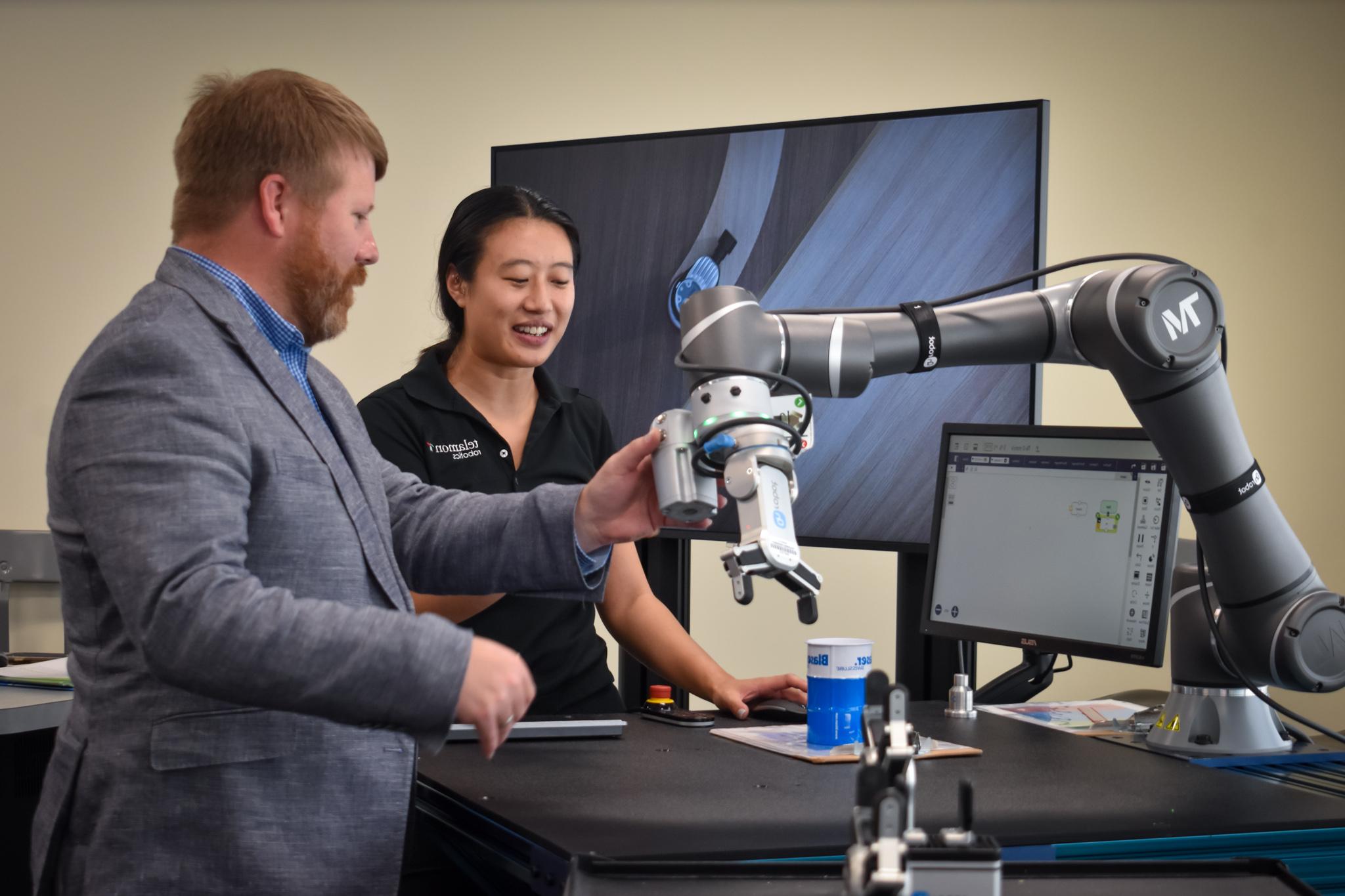 A telamon employee showing a man wearing a suit a mechanical arm